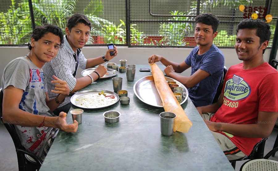 Friends sharing a paper roast dosa at Ambiswamy's